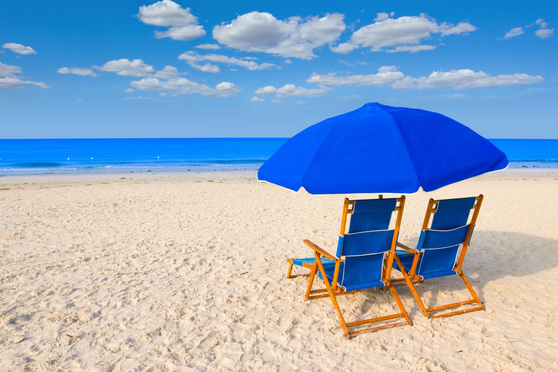 blue beach chairs and umbrella by water